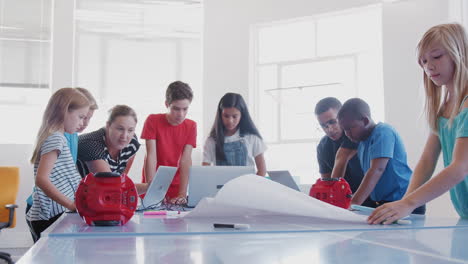 students with teachers in after school computer coding class learning to program robot vehicle