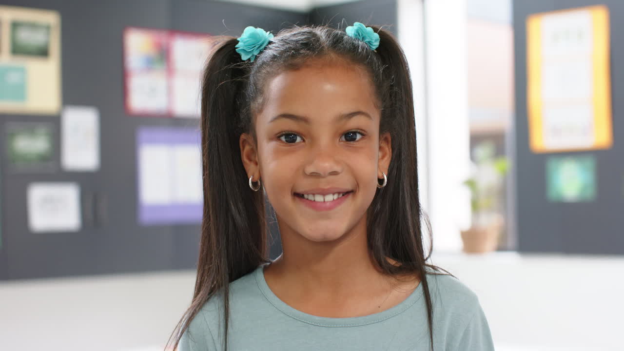 Smiling girl with pigtails in school classroom, looking at camera