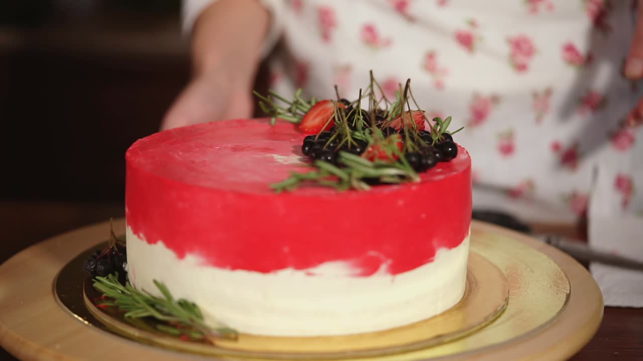 mujer decorando un pastel de terciopelo rojo con bayas y crema