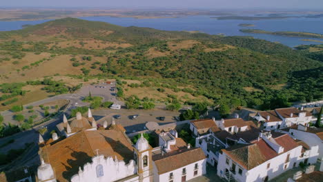 sobrevuelo de drones de la iglesia de nuestra señora de la lagoa hacia el lago alqueva en la distancia, alentejo