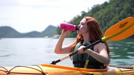 a young adventurer enjoys a refreshing hydration moment while kayaking in a serene waterbody surrounded by lush greenery under clear skies