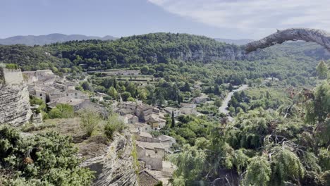 Pequeño-Pueblo-Francés-En-Una-Colina-Entre-Montañas-Y-En-Medio-De-La-Naturaleza-Con-Antiguas-Casas-De-Piedra-Bajo-El-Sol