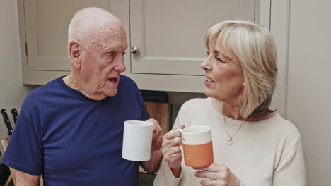 an elderly couple sharing a coffee and conversation in the kitchen