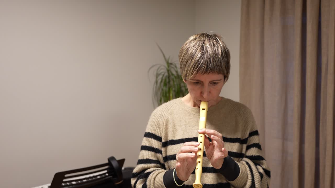 Mujer tocando la flauta dulce y practicando música en casa