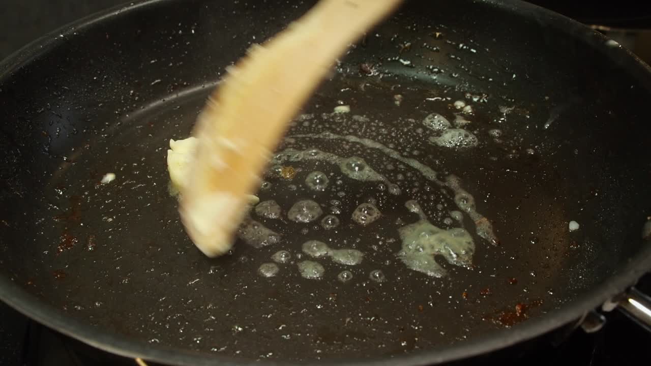 Spoon of butter melts in hot non-stick pan, domestic kitchen cooking