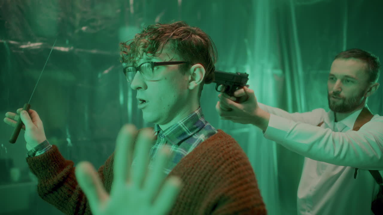 정신병자 범죄자가 칼을 떨어뜨리면서 형사가 그의 머리에 총을 겨누고 있습니다.