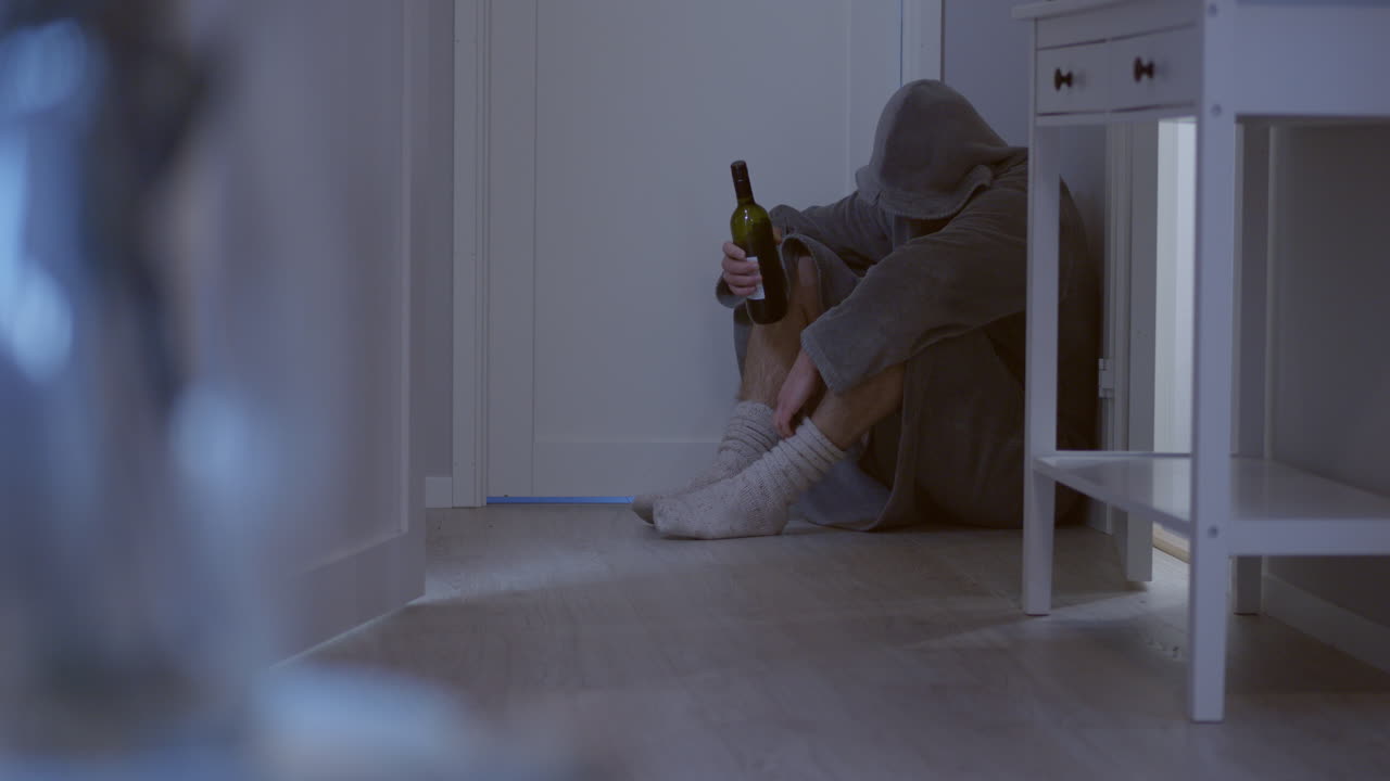 와인 한 병을 들고 방 구석에 웅크리고 있는 남자