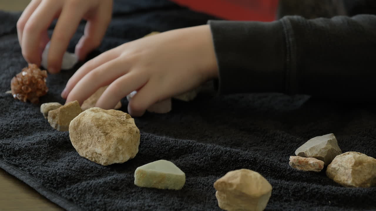 vista de arriba hacia abajo de un niño moviendo piedras sobre una toalla