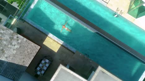 Immerse-yourself-in-tranquility-with-this-top-down-aerial-view-of-a-swimmer-gliding-through-an-infinity-pool