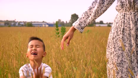 awesome asian kid runs near his mother joyfully in countryside on yellow field