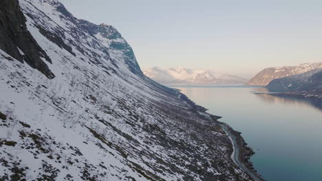 empinadas laderas nevadas de montañas en grotfjord en el norte de noruega - toma aérea
