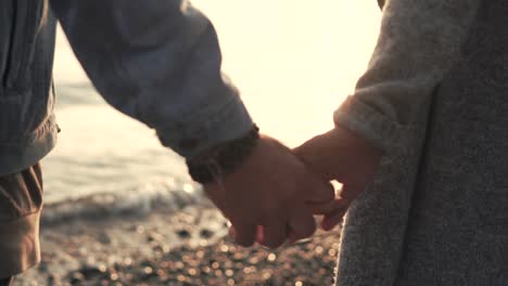 couple holding hands at sunset on the beach