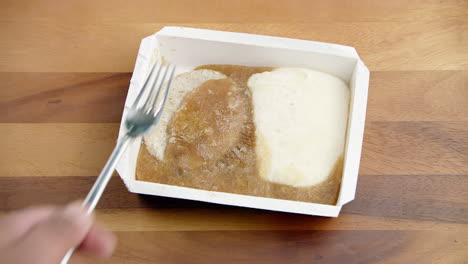 comida empacada congelada que se golpea con un tenedor de metal de acero en la mesa con hambre