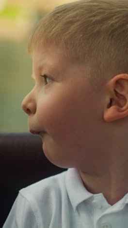 amazed little boy looks around sitting in motorboat salon closeup. curious preschooler child enjoys vessel riding on family vacation. cute little kid