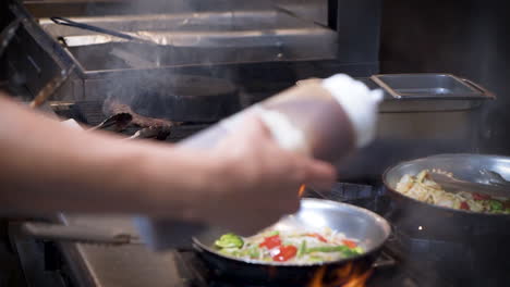 working restaurant kitchen, chef adds sauce to various orders with squeeze bottle, a variety of dishes cook on stove top in traditional commercial restaurant kitchen, slow motion slider hd