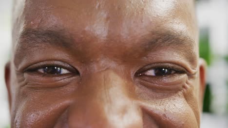 Portrait-of-happy-african-american-businessman-looking-at-camera-and-smiling-at-office,-slow-motion