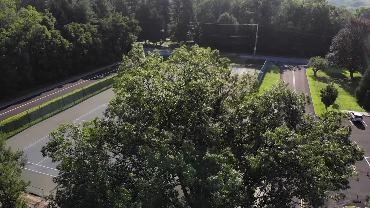 4k дронный снимок теннисного корта, появляющегося сквозь деревья