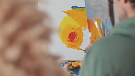 an unrecognizable man painting with a spatula on a canvas