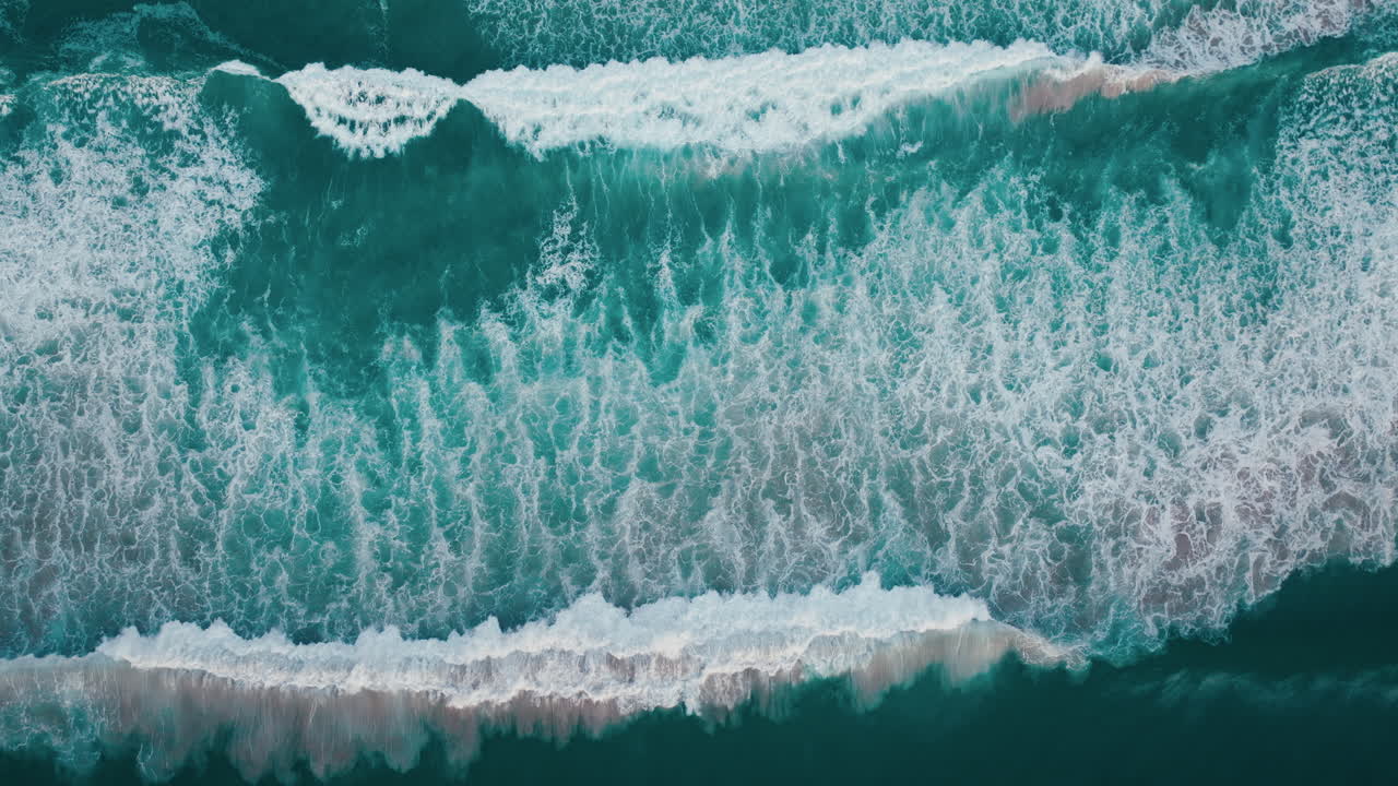 Top down drone of white surf advancing over dark blue water near Byron Bay coast, ocean stunning tendril backdrop