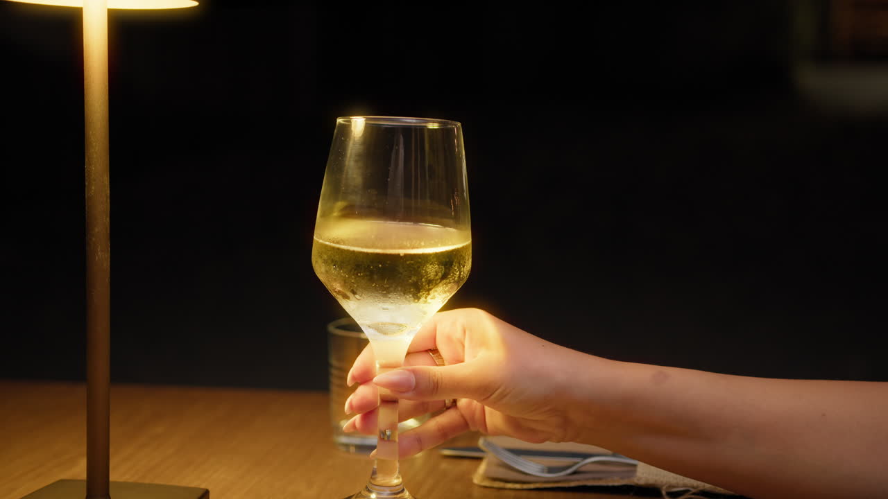 Light Of The Lamp Over The Glass Of Gold Wine At The Restaurant Table