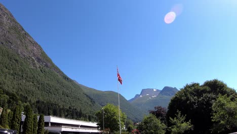 norway flag blowing in wind during summer day in national romantic landscape - static loen norway