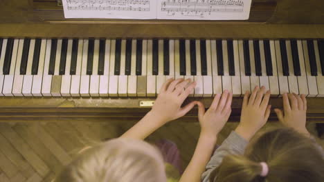 top view of two little girls playing old piano at home