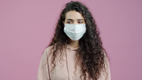 woman wearing mask in front of pink background