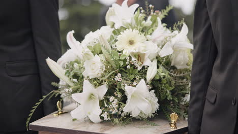 carrying coffin, flowers and people at funeral