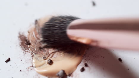 blending a dark-brown toned mascara loose powder using an eyelash wand applicator on a blank white board