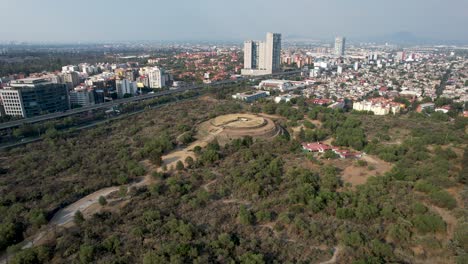 tomada orbital derecha del núcleo de la pirámide azteca de cuicuilco en la ciudad de méxico y un edificio residencial cerca