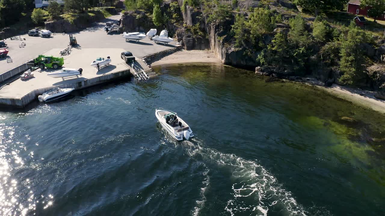 트럭과 트레일러가 주차된 정박지에서 보트가 부두에 접근합니다.