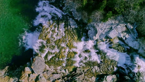 top down shot of fast moving river with rapids surrounded by green forest in norway at daytime