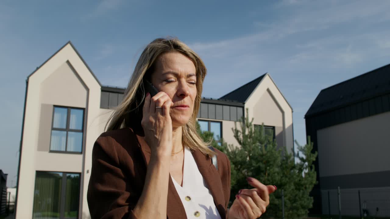 Frau telefoniert vor modernen Häusern