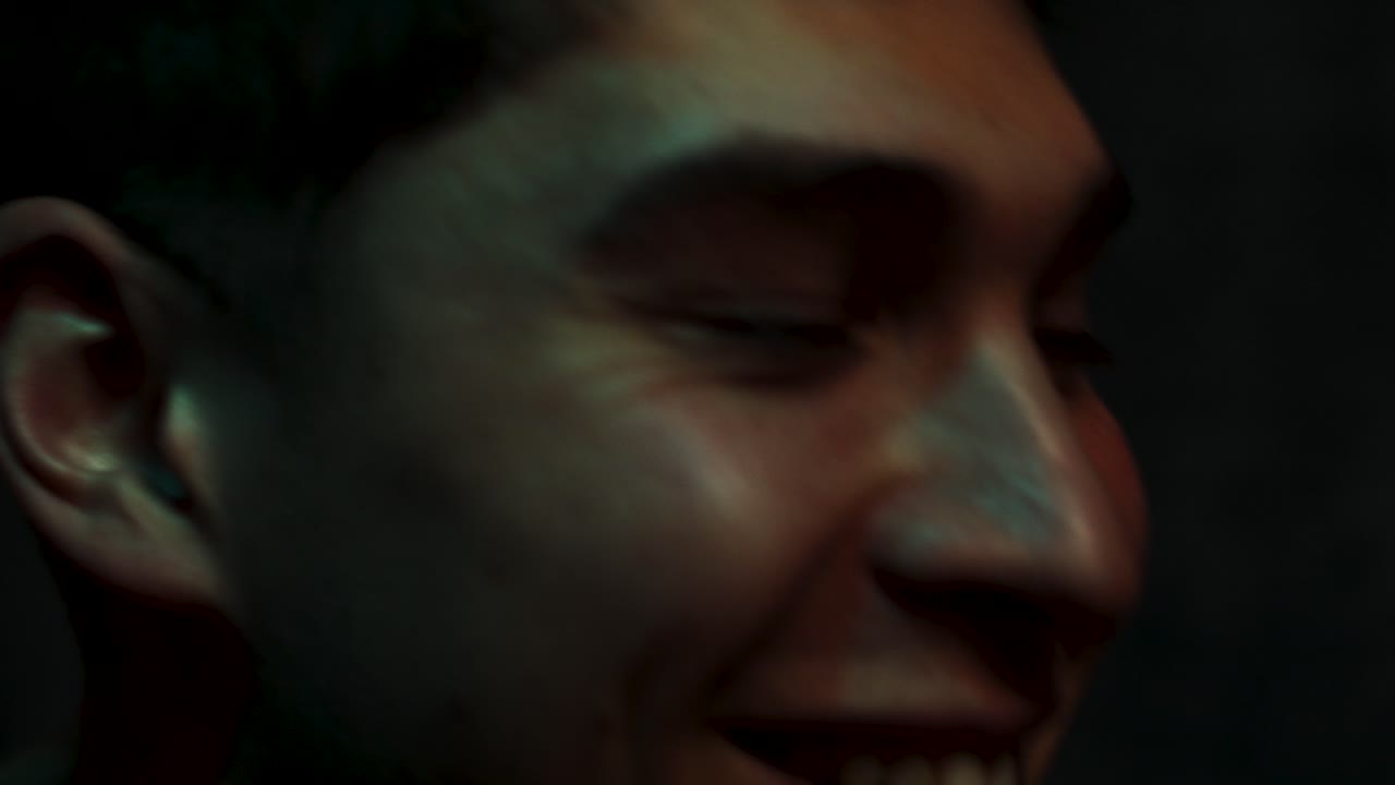 Man laughs at the cinema face lit up in a dark room