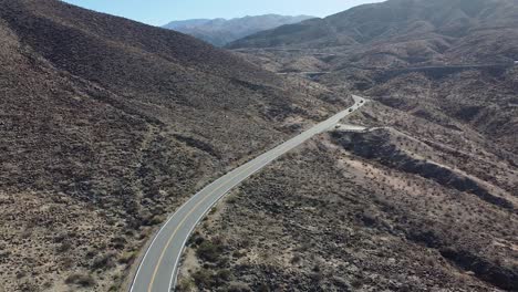 Wüstenberglandschaft-Mit-Kurvenreicher-Straße-Und-Fahrenden-Fahrzeugen,-Luftaufnahme