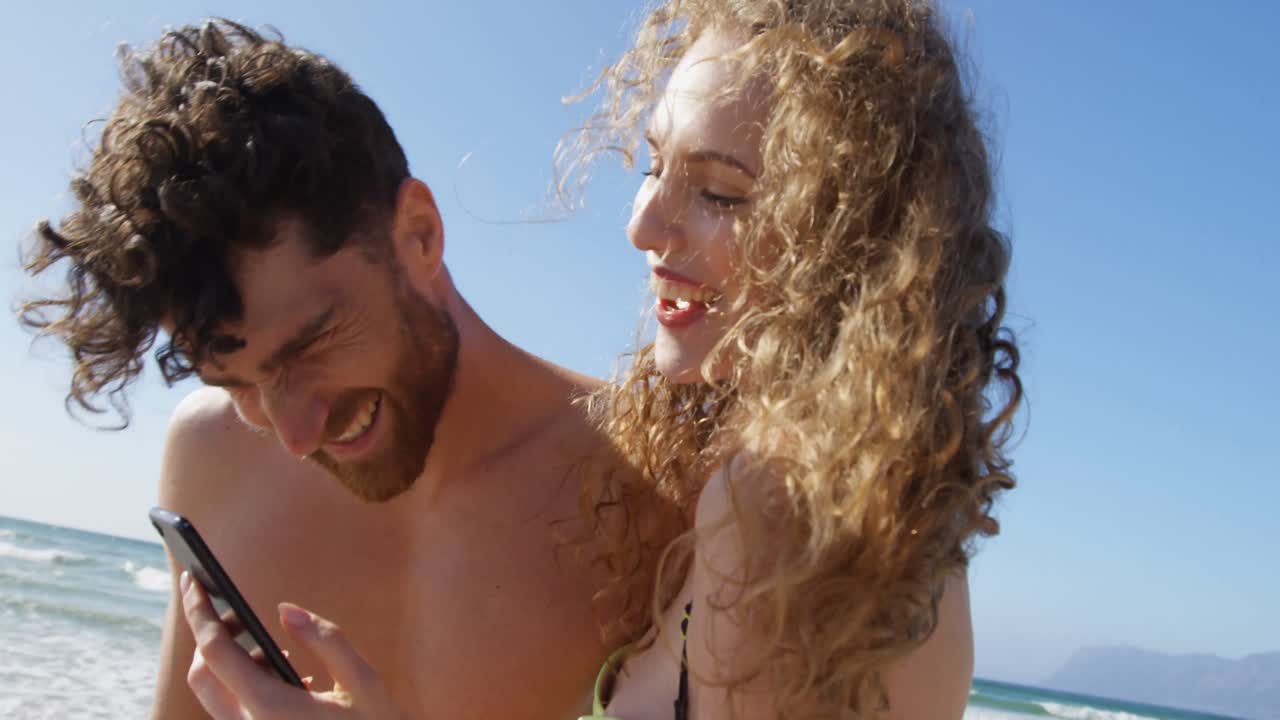 Romantic couple using mobile phone at beach 4k