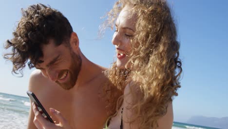 romantic couple using mobile phone at beach 4k