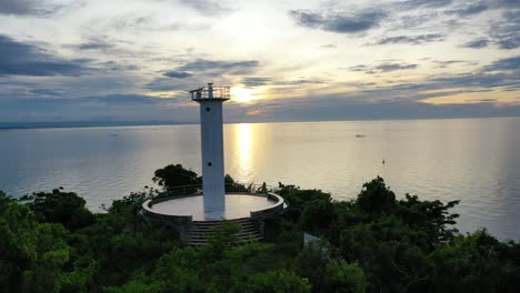 a lighthouse sits in the top of a mountain near the ocean where it is properly placed and has a stunning view of the sea during sunset