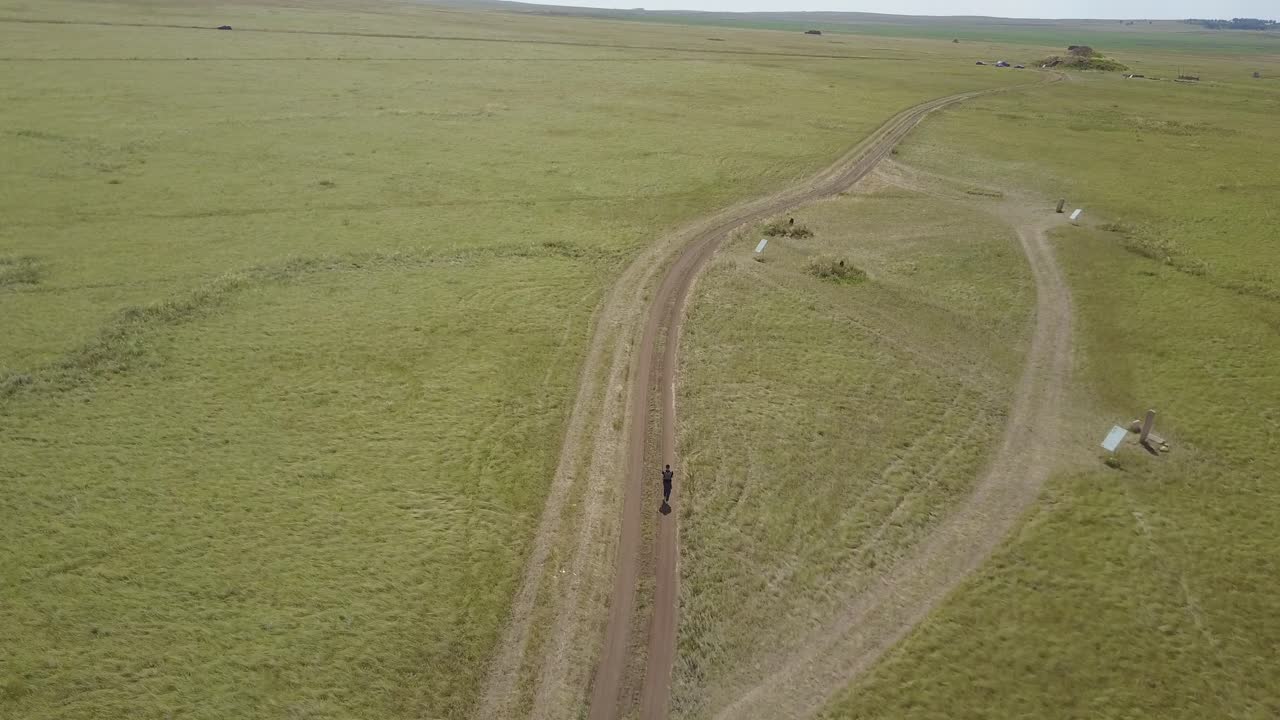 persona caminando por un camino de tierra en un campo de hierba