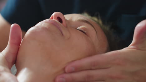 woman lies relaxed with eyes closed while practitioner gently massages gel across cheeks and forehead, highlighting glowing hydrated complexion and calm spa treatment atmosphere