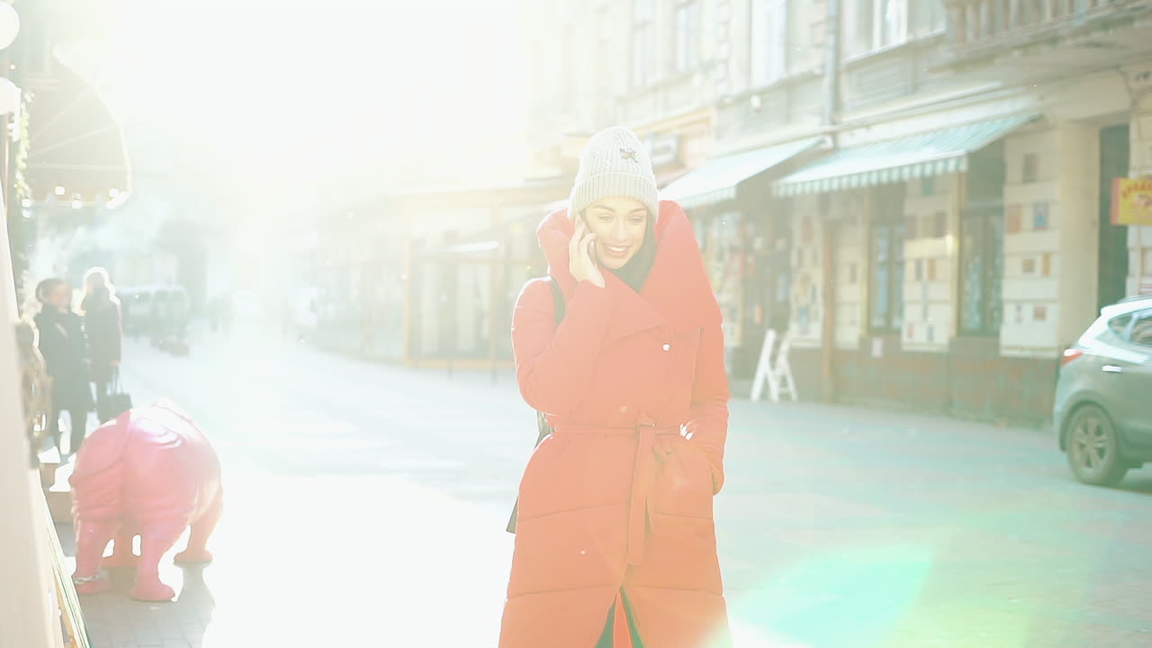 Woman in Red Coat Talking on Phone on City Street