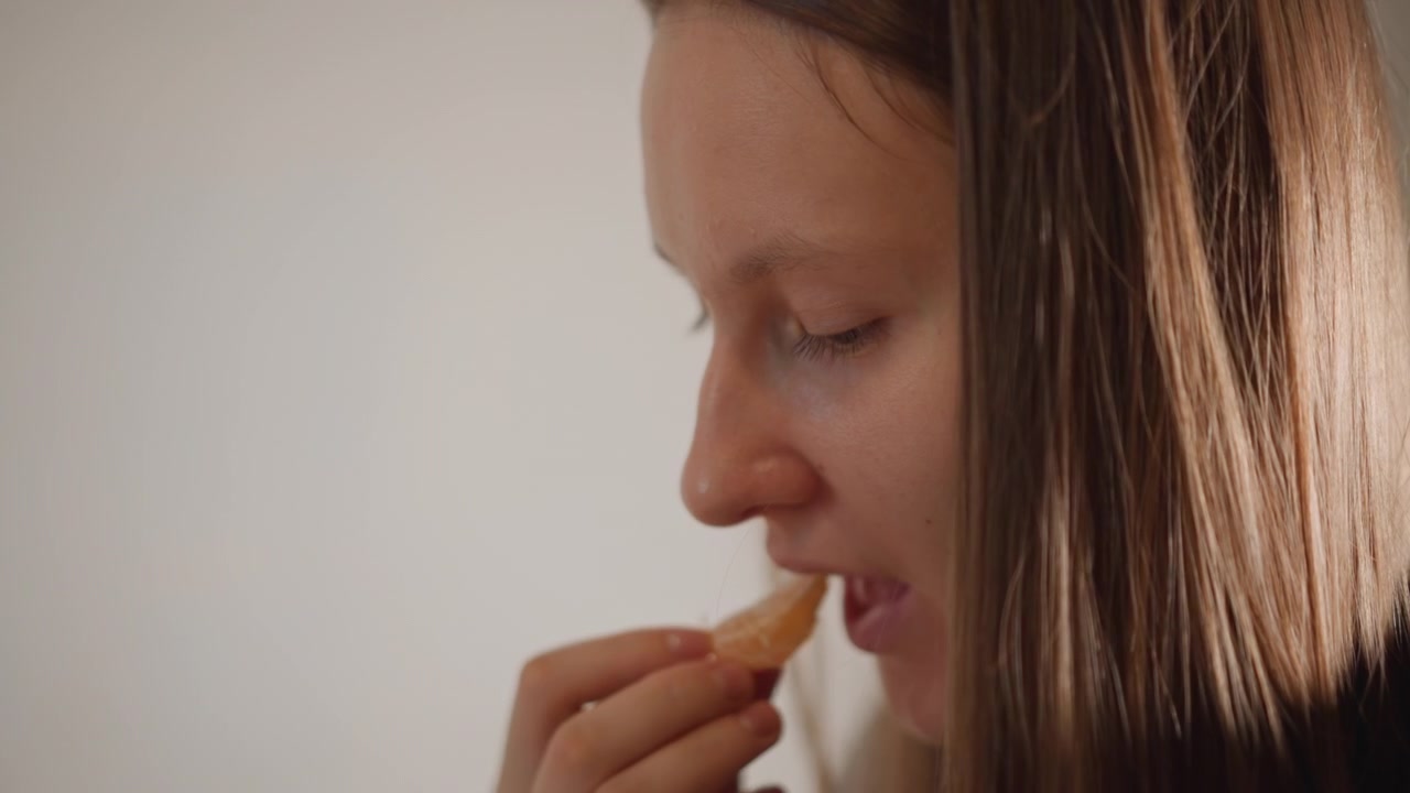 Elegant woman savors tasty snack. Caucasian woman fondly relishes flavored crunchy bite at home. Graceful lady enthusiastically enjoys textured crispy snack within comfort of her residence
