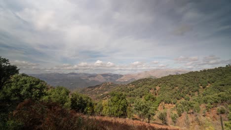 green trees and rocky mountain of spain with flowing clouds above, time lapse