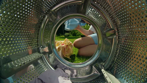 person loading laundry into a washing machine in a garden