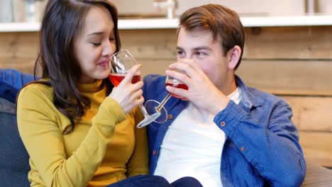 smiling couple toasting a glasses of wine in living room