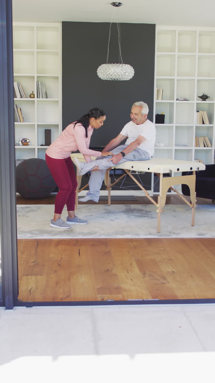 video vertical de una fisioterapeuta bi-racial feliz haciendo ejercicio con un paciente mayor