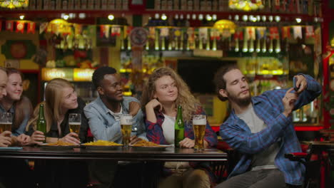 group of young friends drinking and laughing in a bar