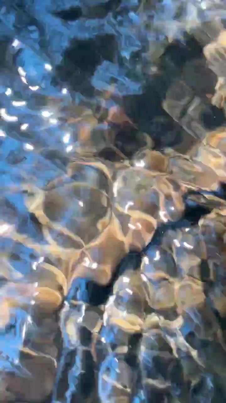Acqua limpida che scorre su ciottoli di fiume lisci.