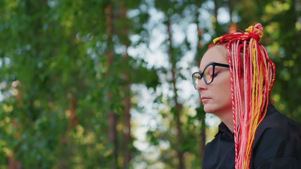 vista de perfil de una mujer sorprendida en la naturaleza, una mujer con trenzas muestra sorpresa en un entorno frondoso, un transeúnte observador se fija en una mujer blanca con rasgos expresivos y pelo llamativo en un parque exuberante