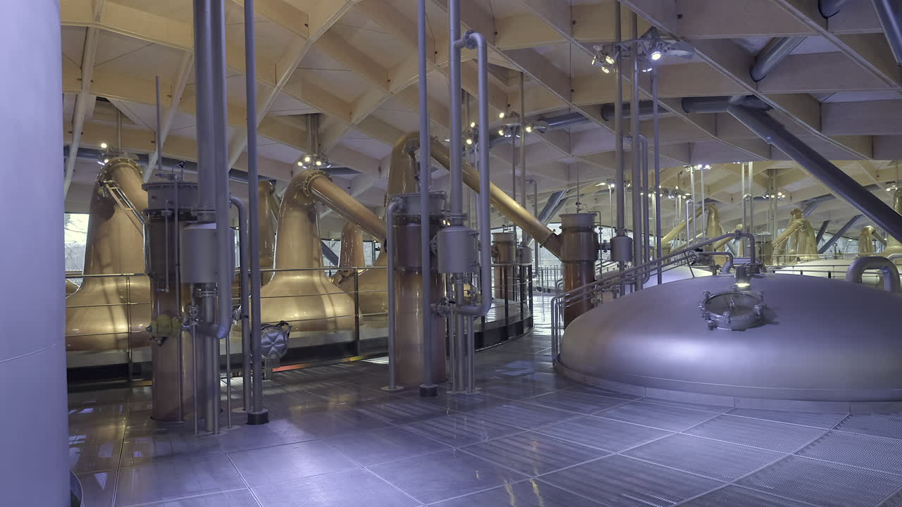Innenansicht von Rohrleitungen, Kupferbrennblasen und Maischebottichen, die die Architektur und Komplexität einer modernen schottischen Whiskybrennerei hervorheben.